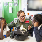 Female pilot in uniform talks with two excited students about aviation