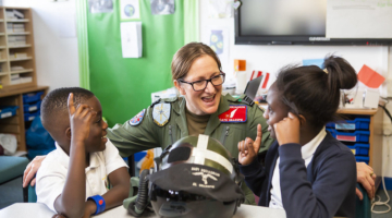Female pilot in uniform talks with two excited students about aviation