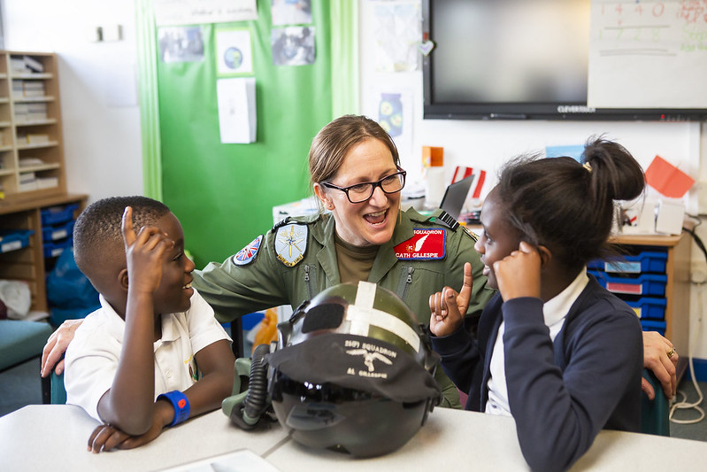 Female pilot in uniform talks with two excited students