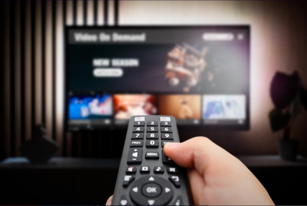 Person with a remote control switching channels on tv.