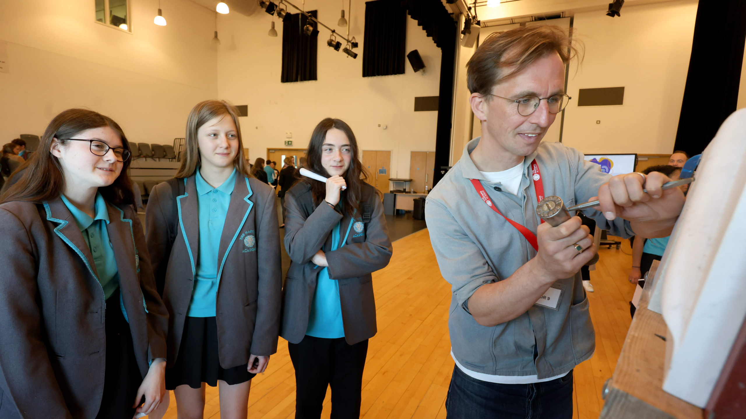 stonemason showing students his craft while three secondary students look on - QEST event