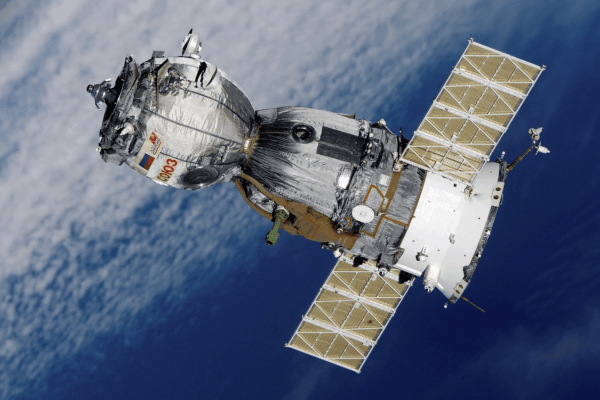 Satellite with solar panels orbiting above Earth, showcasing advanced space manufacturing and technology.