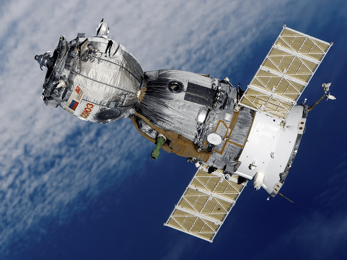 Satellite with solar panels orbiting above Earth, showcasing advanced space manufacturing and technology.